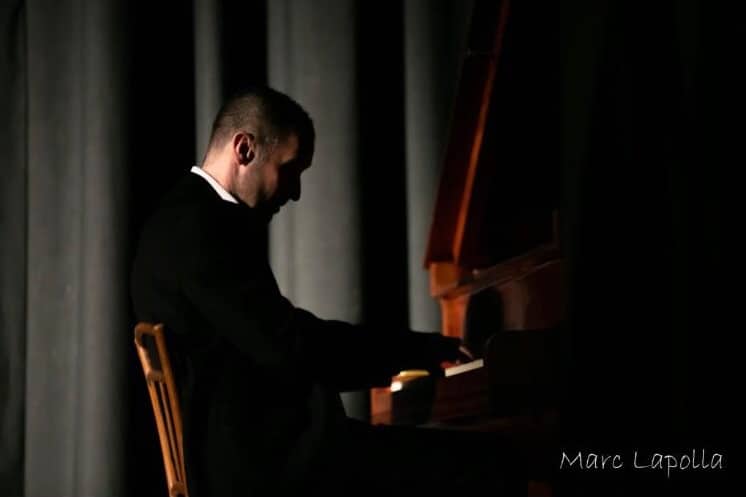 Pianiste en plein concert jouant un morceau sur un piano, éclairé par une lumière tamisée dans une ambiance intime.