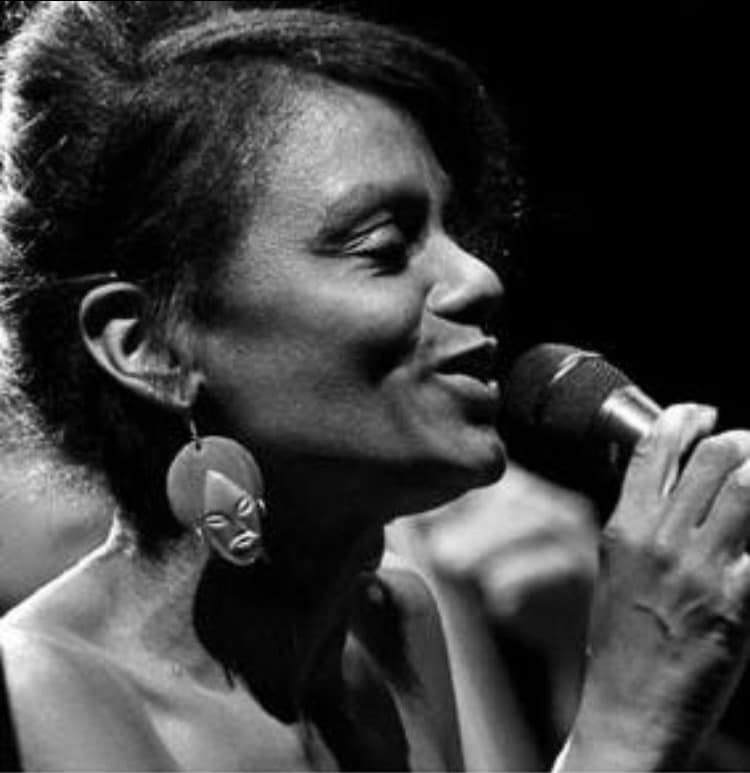 Denia Ridley, chanteuse de jazz, interprétant une chanson avec émotion lors d'une prestation live, micro en main, capturant toute la passion du jazz.